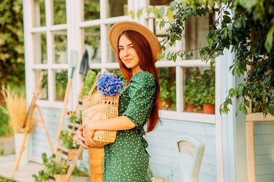女人在绿色和白色圆点连衣裙布朗编织篮子
